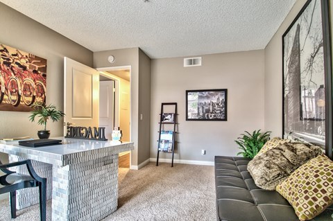 A living room with a black couch and a bar area.