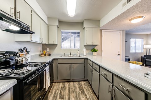 A kitchen with black stove top and white counter tops.