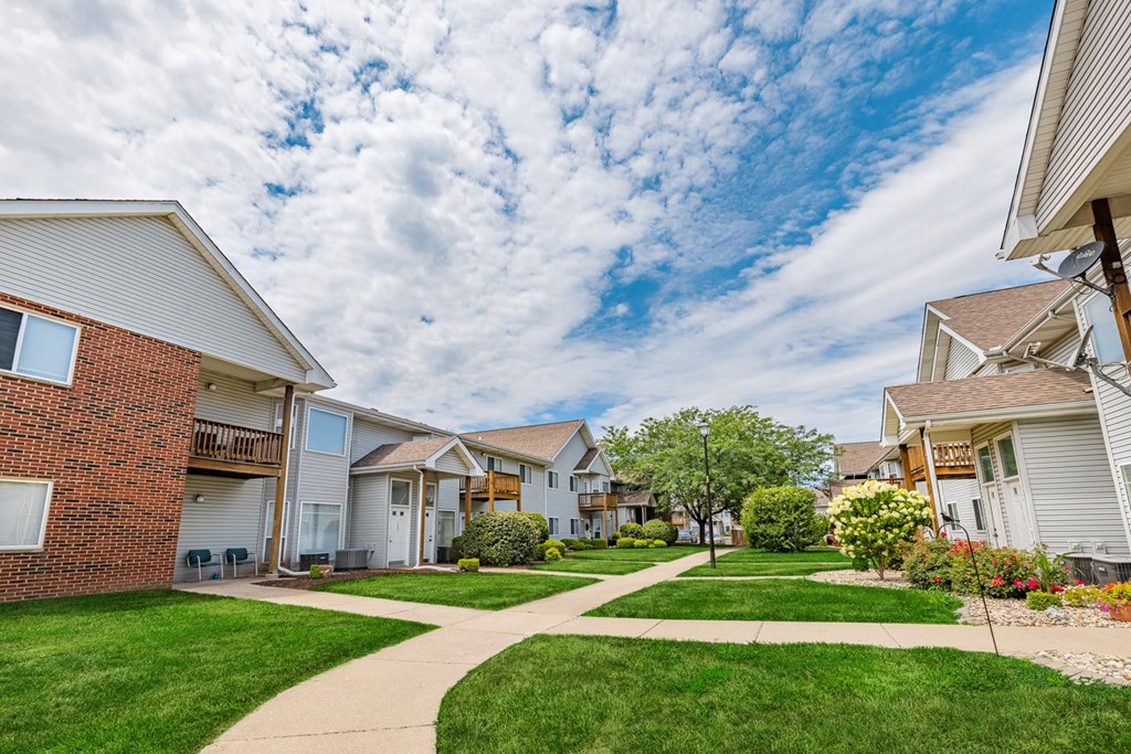 a sidewalk in front of houses on a green lawn