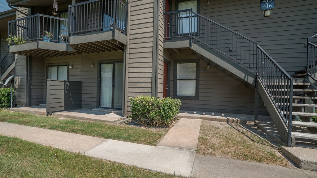 an apartment building with stairs and a sidewalk