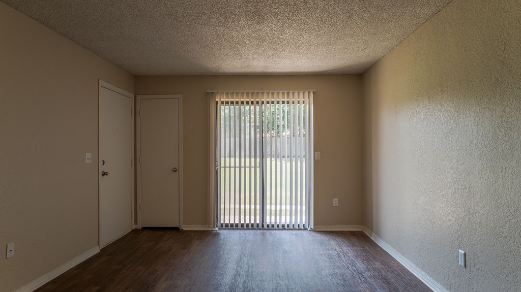 an empty living room with a door to a balcony
