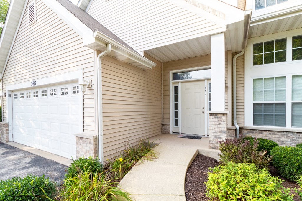 a sidewalk in front of a house with a garage door