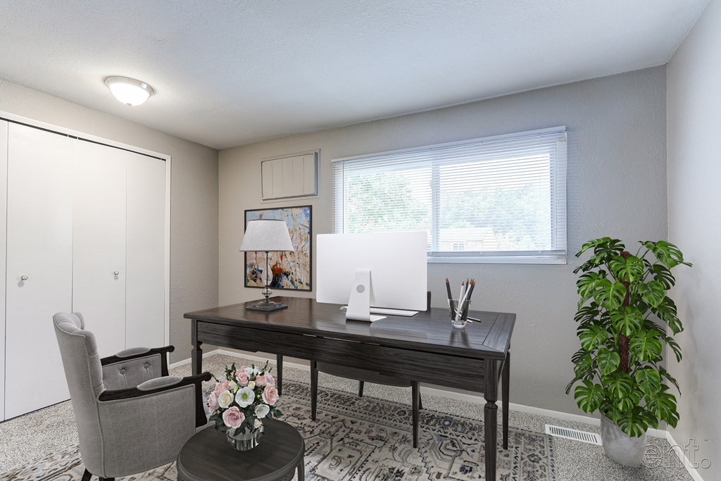 A room with a desk, chair, and potted plant.