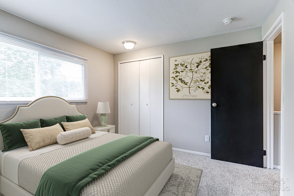 A bedroom with a bed, nightstand, and a painting on the wall.