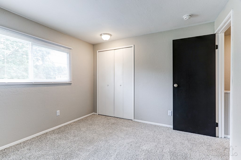 A room with a black door and a window with blinds.