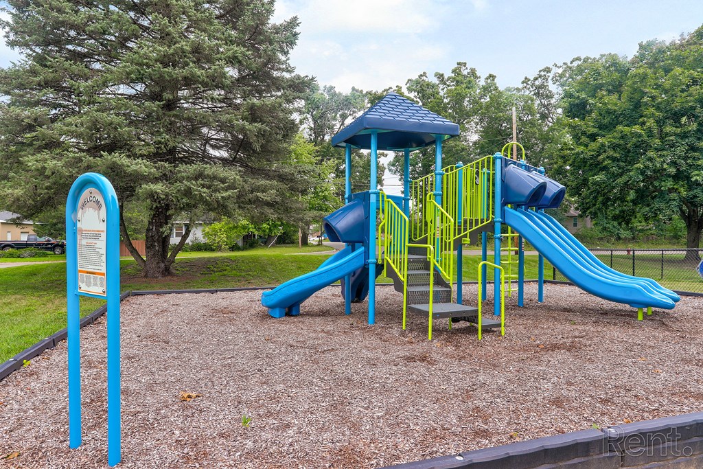 A playground with a blue slide and yellow railing.