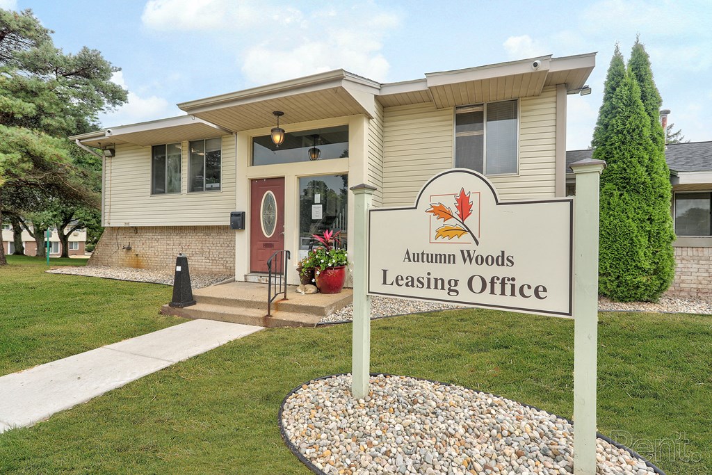 A sign for Autumn Woods Leasing Office in front of a building.