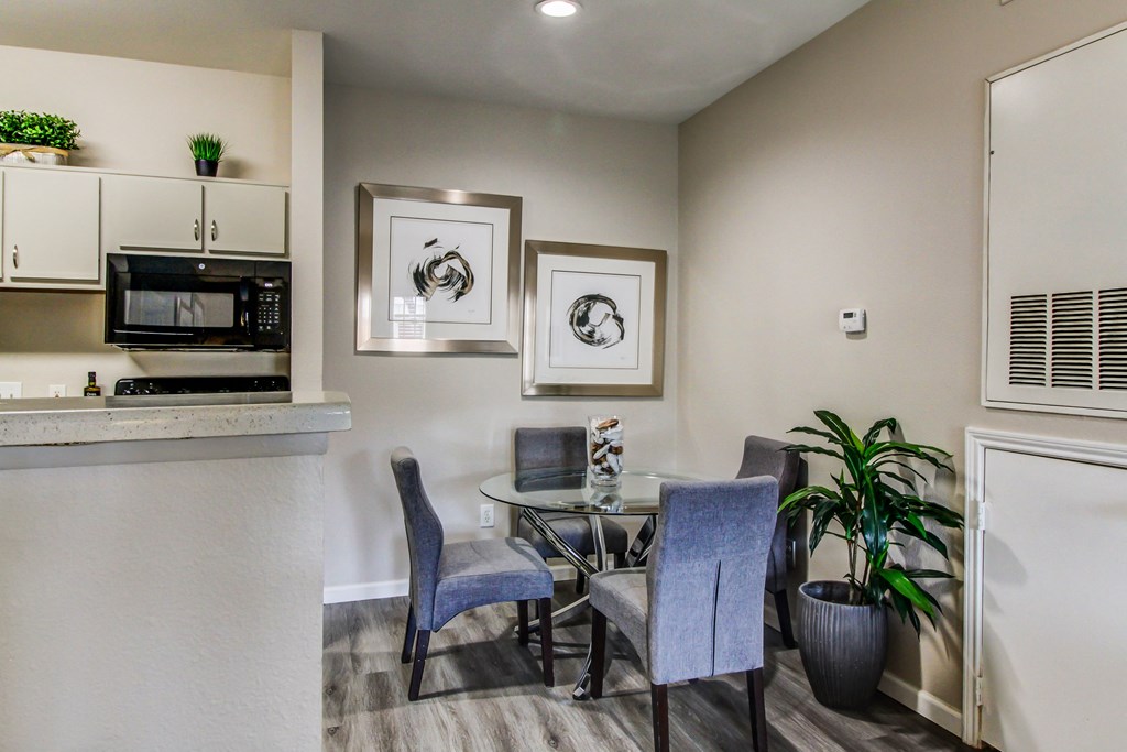 a dining area with a glass table and chairs and a kitchen with a microwave