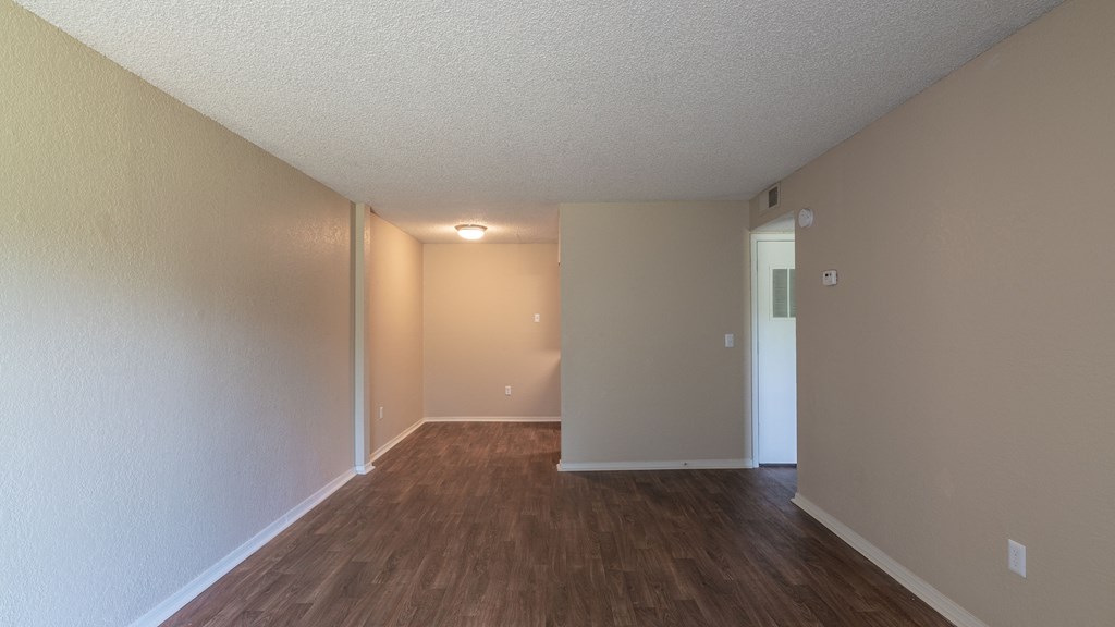 the spacious living room and dining room of an apartment