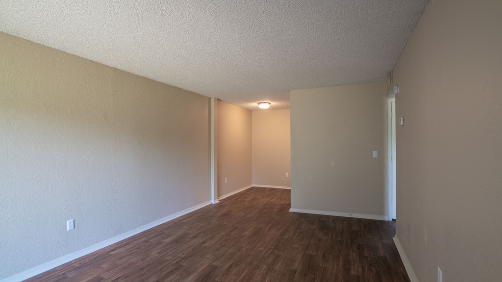 an empty living room with wood flooring and white walls
