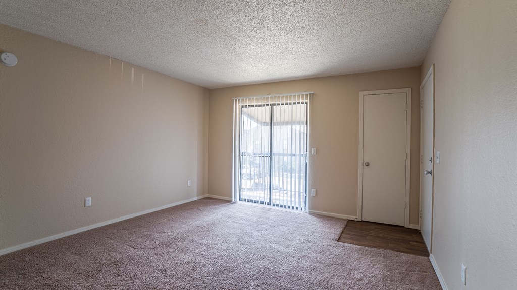 an empty living room with a door to a balcony