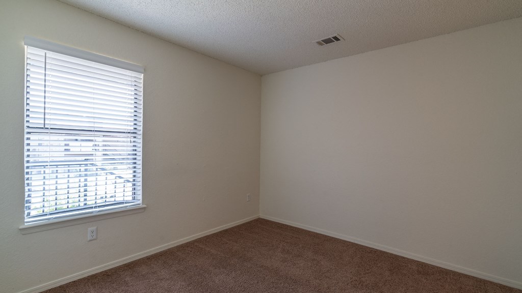 an empty bedroom with a large window and carpeting