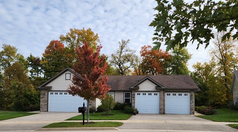 a white house with two garage doors in front of a tree