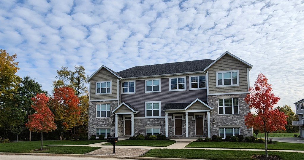 a house on a street with clouds in the sky