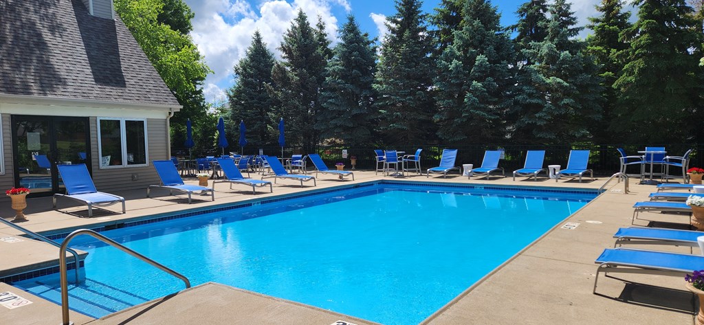 a swimming pool with blue lounge chairs around it and a house with a pool