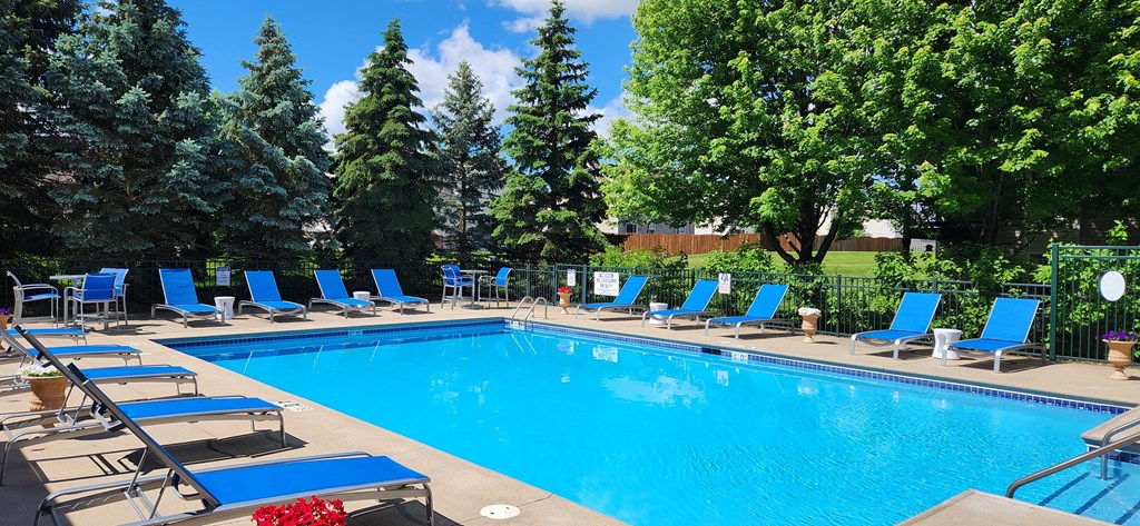 a swimming pool with blue lounge chairs around it