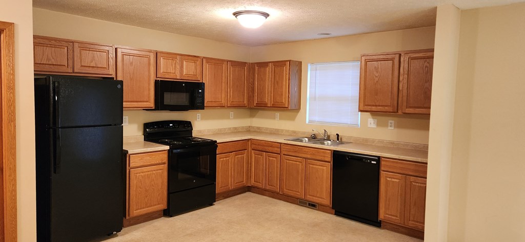 A kitchen with black appliances and wooden cabinets.