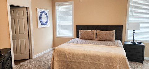 A bedroom with a large bed and a window with blinds.