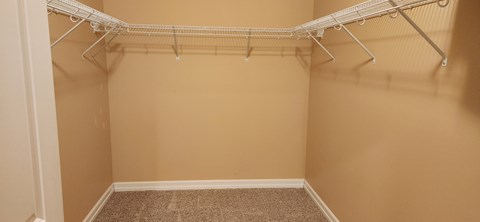 Empty walk-in closet with white shelving.