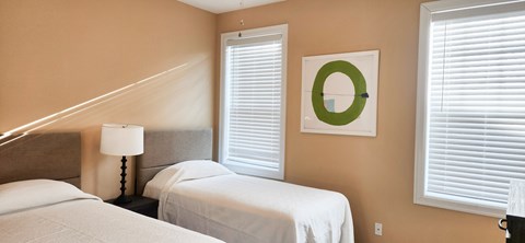 A bedroom with two beds, a lamp, and a picture on the wall.