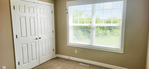 A white door is on the left and a window with blinds is on the right.
