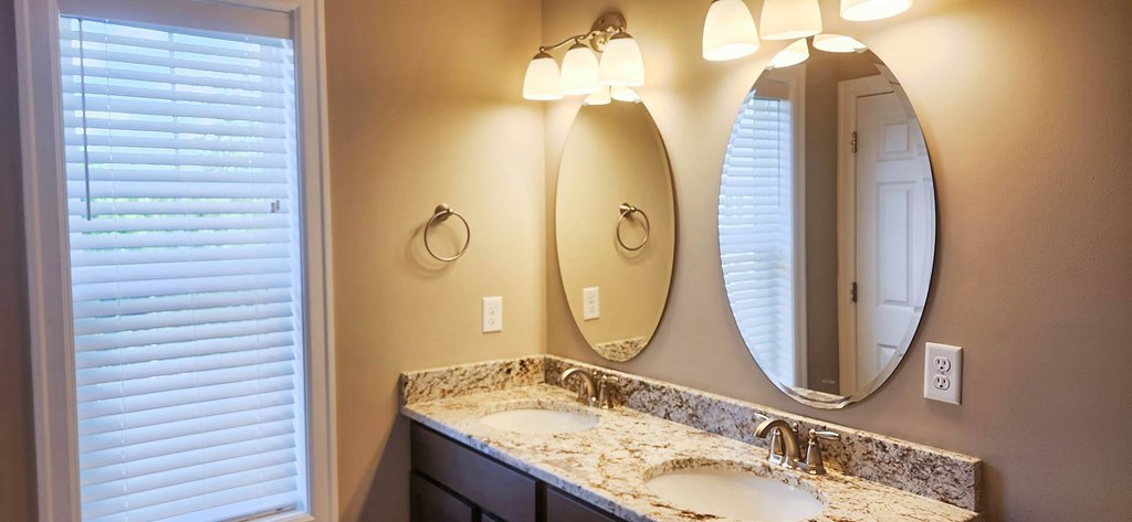 A bathroom with a sink, mirror and lighting.