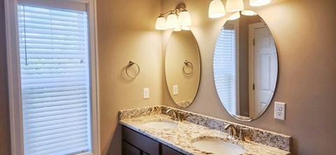 A bathroom with a sink, mirror and lighting.
