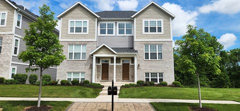 A grey house with a black roof and a brown door.