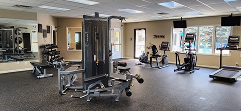 A gym with a variety of equipment including treadmills, weights, and exercise machines.