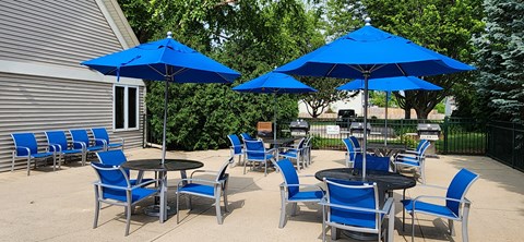 A patio with blue chairs and umbrellas.