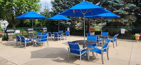 A patio with blue chairs and umbrellas.