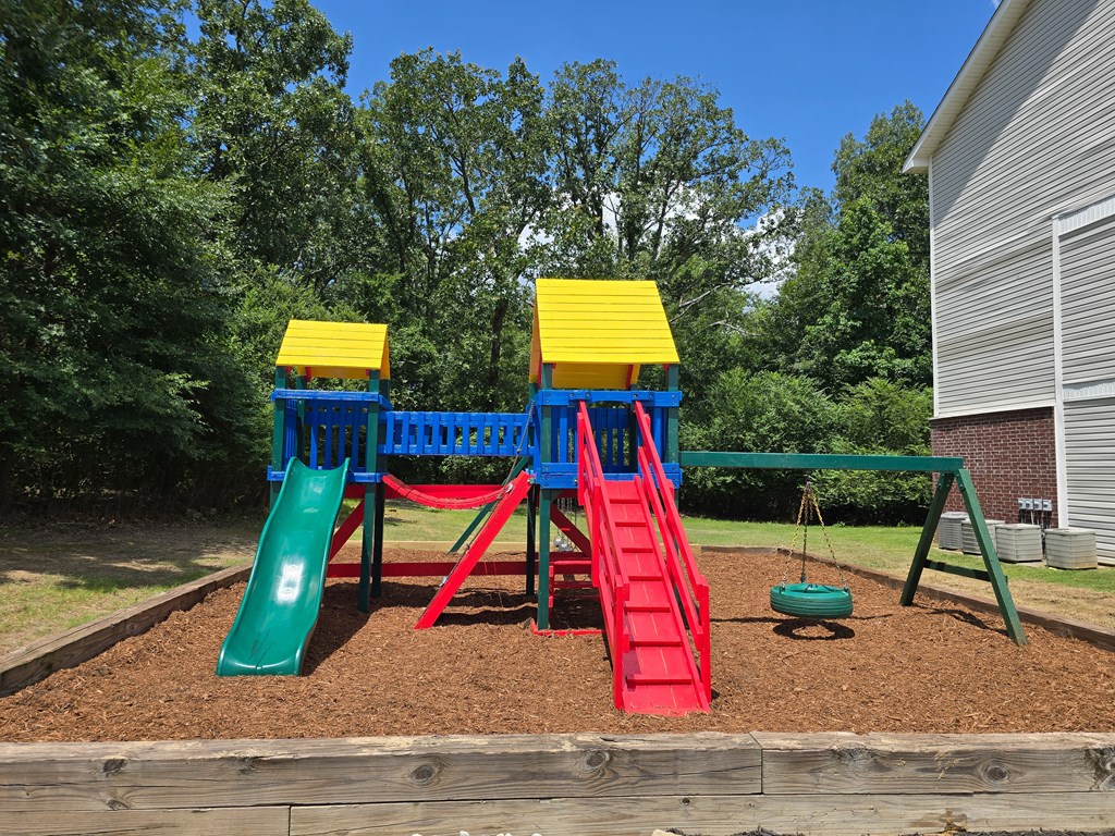 A playground with a red slide, green slide, and yellow and blue platforms.