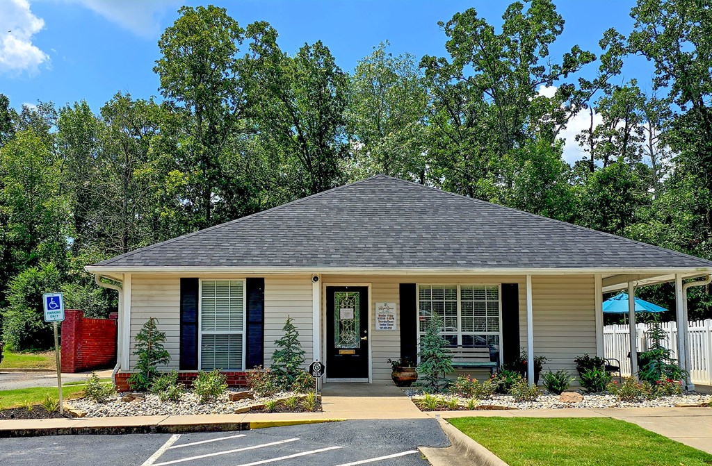 A small house with a black roof and a sign in front of it.