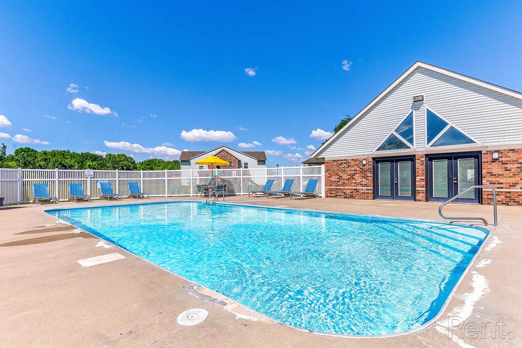 our resort style swimming pool is in front of our building with chairs and a building