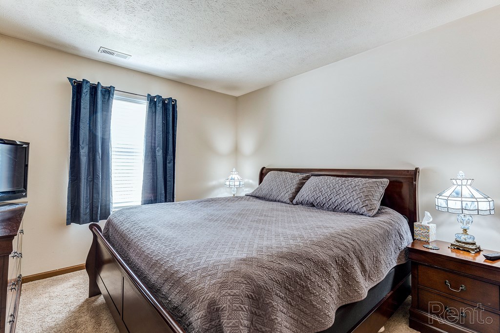 the master bedroom has a king sized bed and a tv