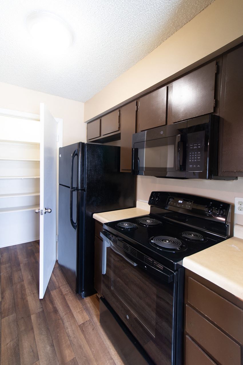 a kitchen with black appliances and wooden floors and a black refrigerator