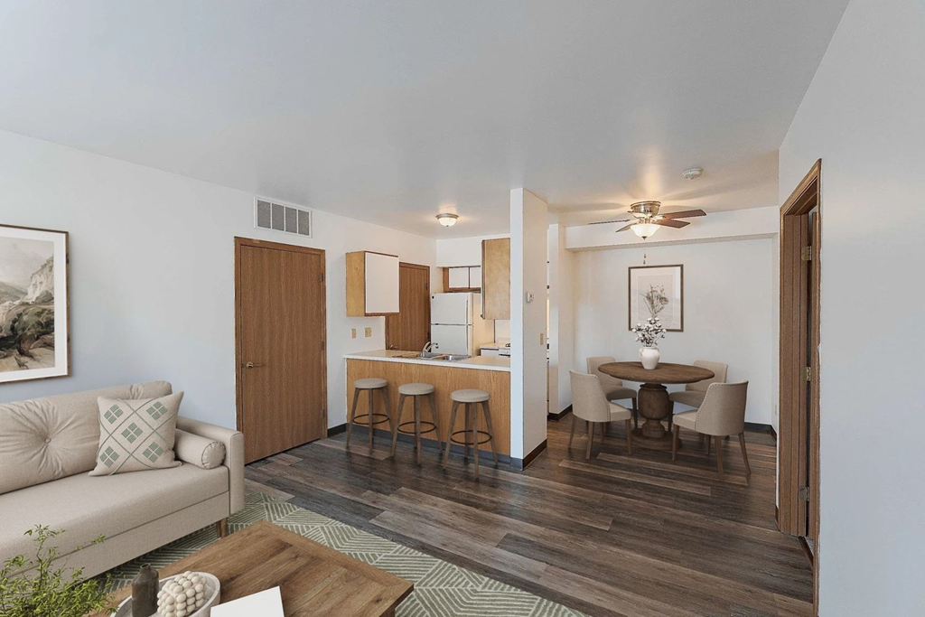 A living room with a couch, a dining table, and a kitchen area in the background.