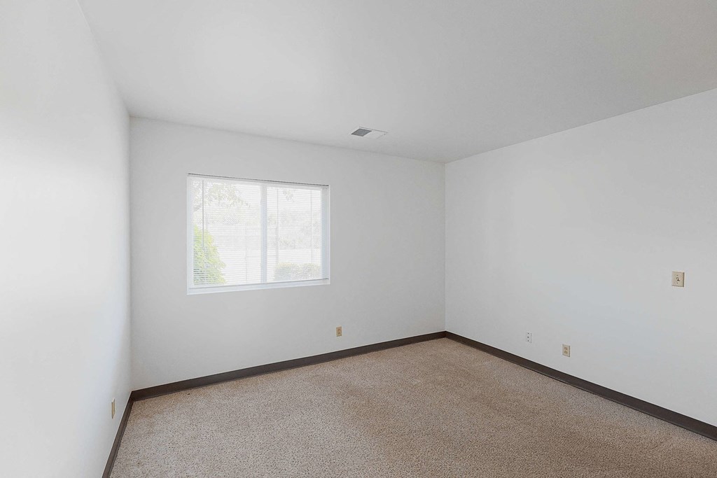 a bedroom with white walls and a window