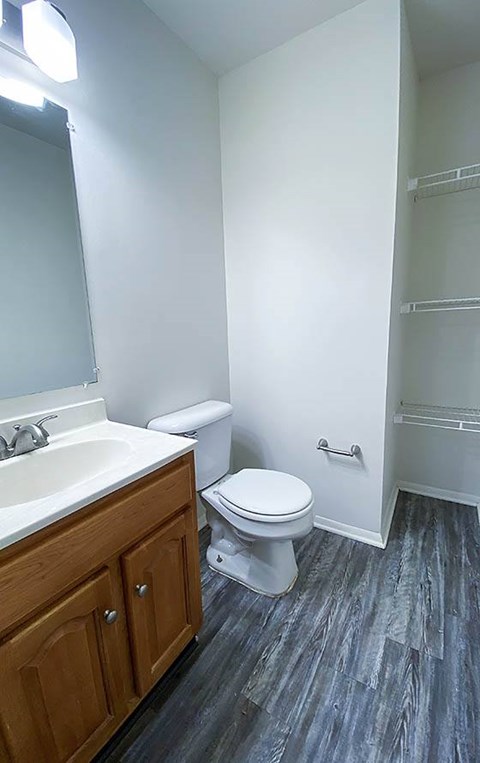 A bathroom with a toilet, sink, and wooden cabinet.
