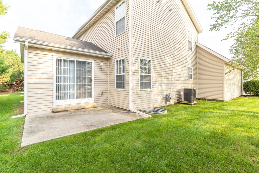the back of a house with a patio and a yard