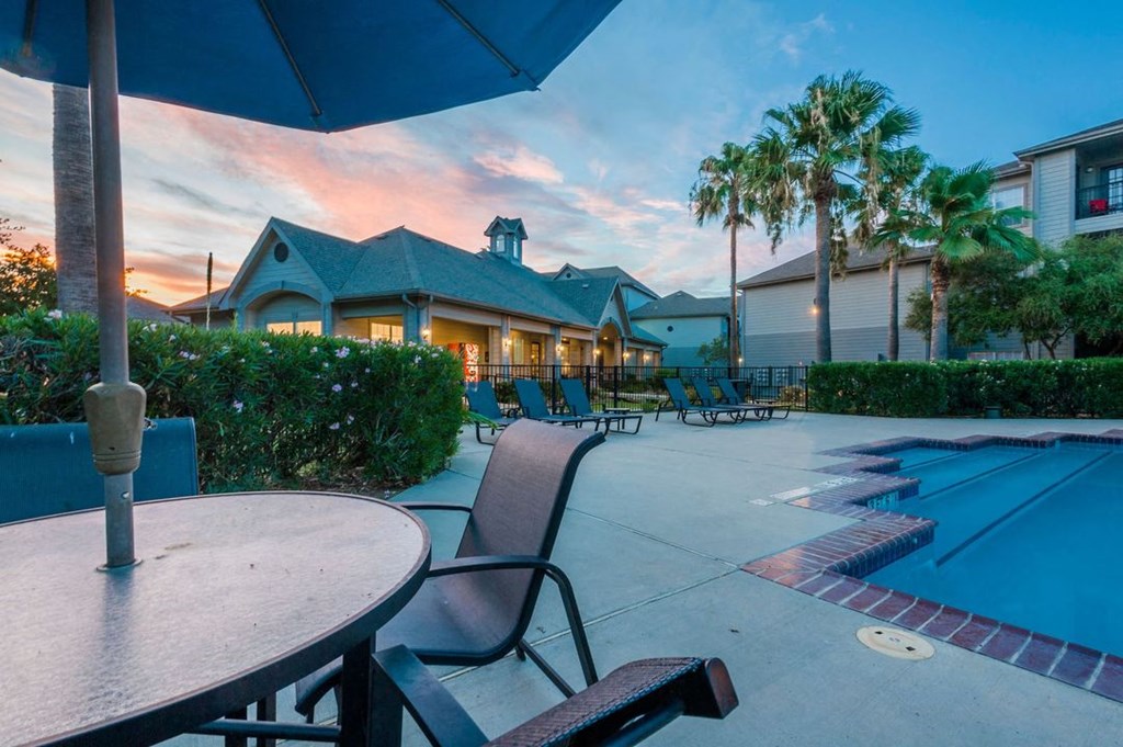 a patio with chairs and a table next to a swimming pool