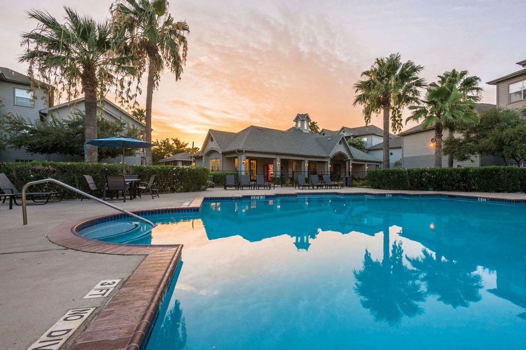 a large swimming pool with palm trees and a building in the background