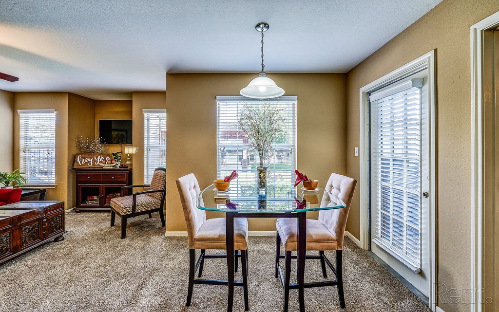 a dining room with a glass table and chairs and a large window