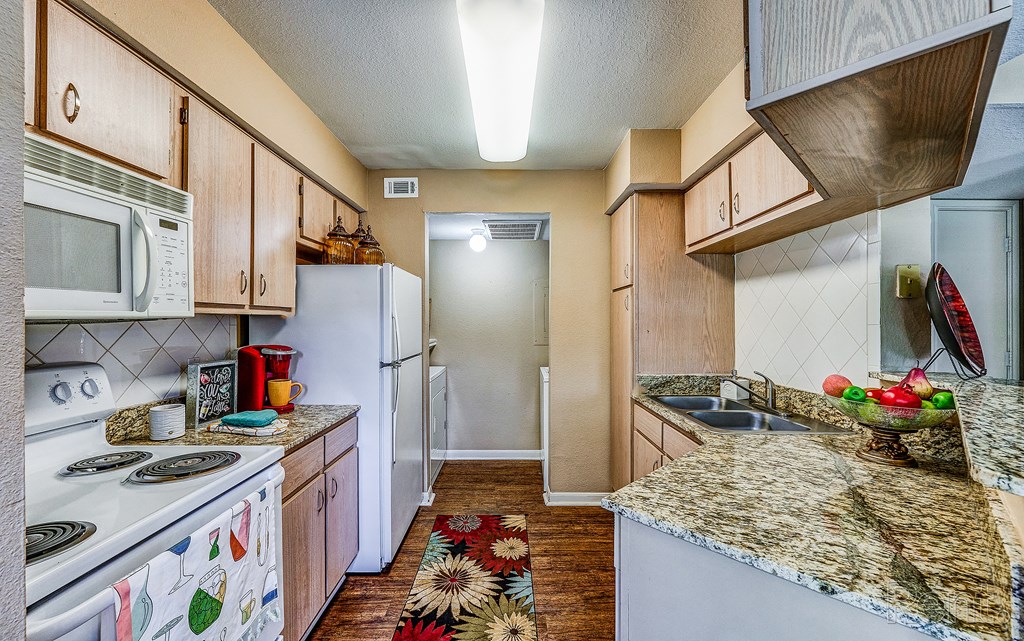 a kitchen with white appliances and granite counter tops