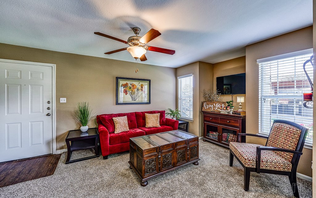a living room with a red couch and a ceiling fan