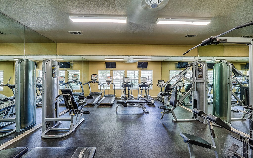 a gym with cardio equipment and weights on the floor