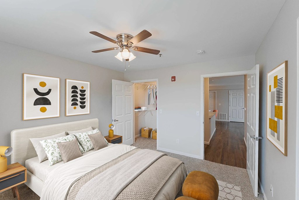 A bedroom with a bed, a ceiling fan, and artwork on the wall.