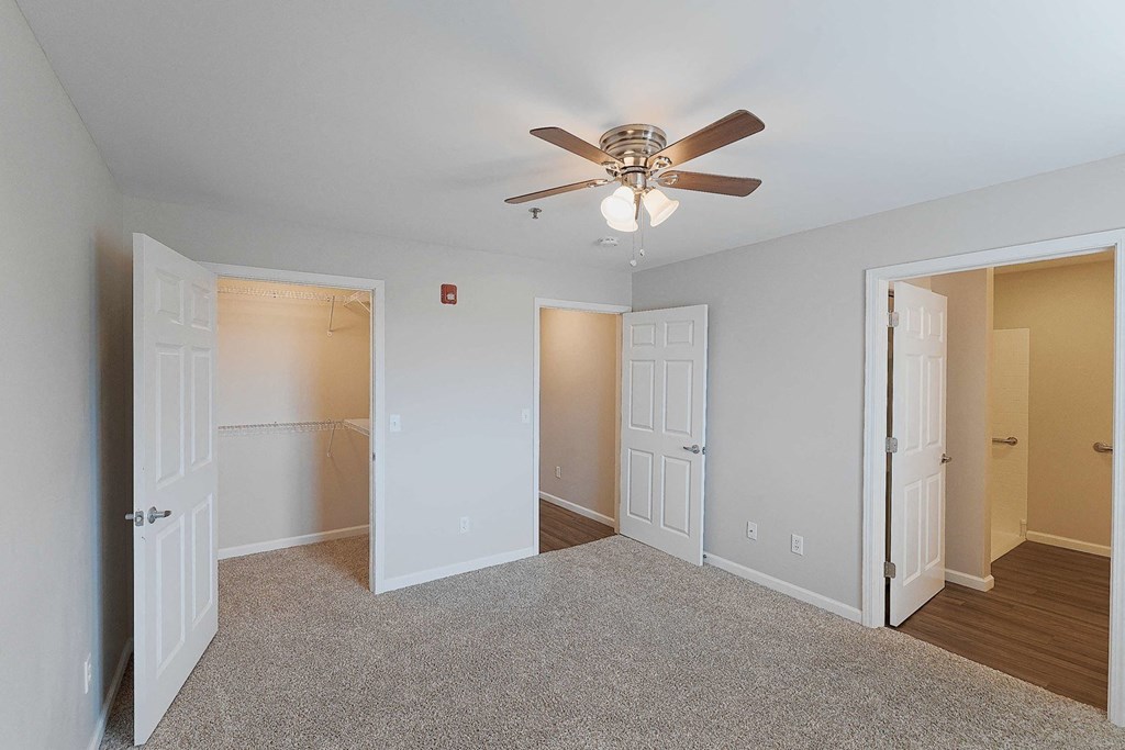 a bedroom with two closets and a ceiling fan