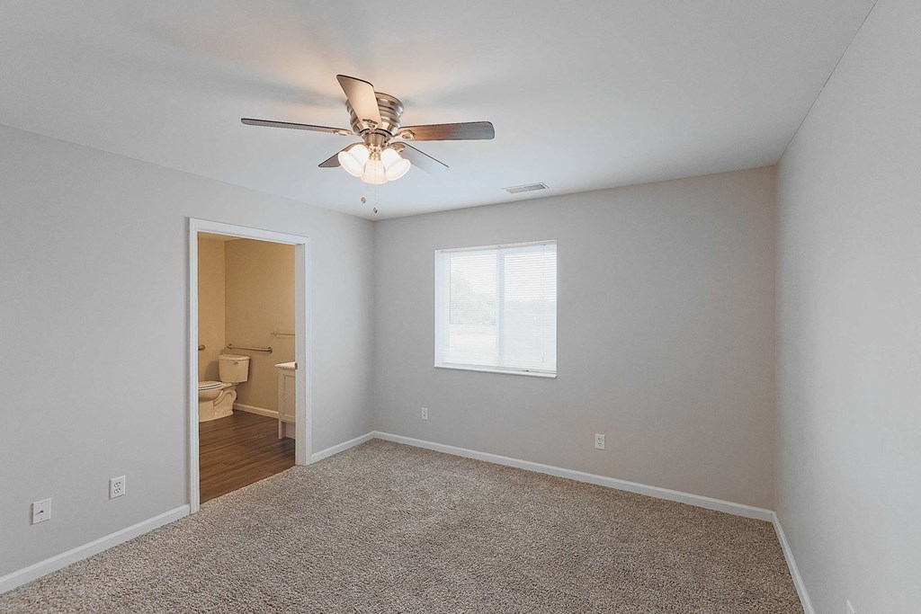 a bedroom with a ceiling fan and a door to a bathroom