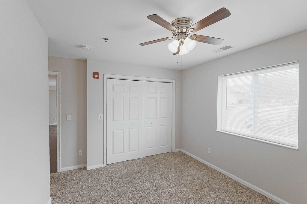 an empty bedroom with a ceiling fan and a closet